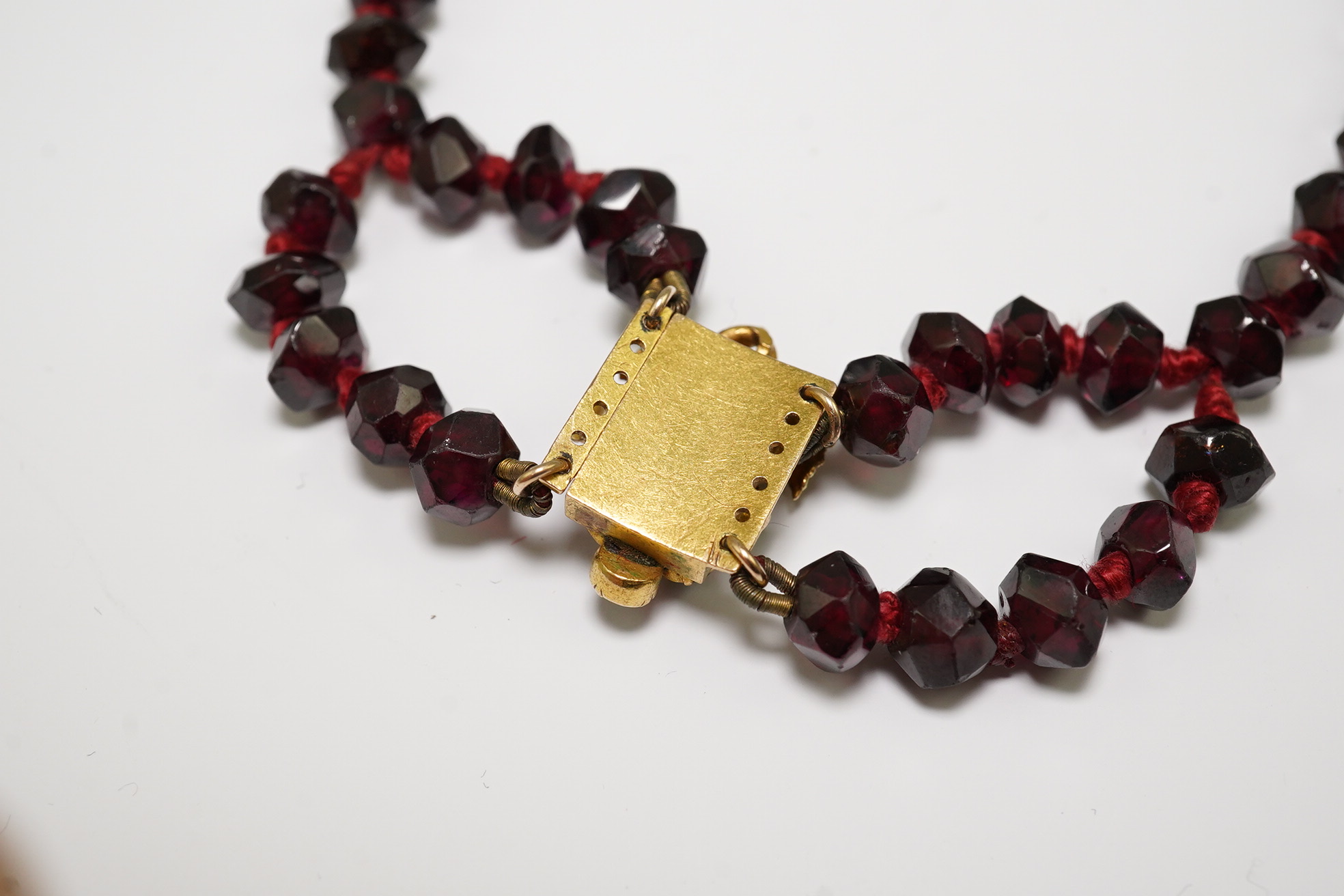 A Victorian facet cut garnet necklace, with cabochon garnet cluster set gold clasp